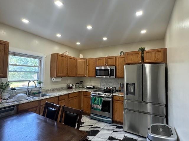 kitchen featuring sink, light stone countertops, stainless steel appliances, and tasteful backsplash