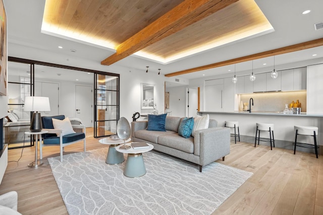 living room with sink, light hardwood / wood-style flooring, wooden ceiling, and beamed ceiling