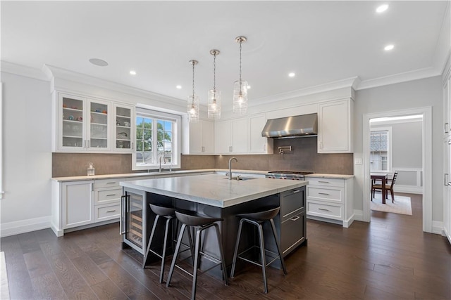 kitchen with a center island with sink, white cabinetry, dark hardwood / wood-style floors, and wall chimney range hood