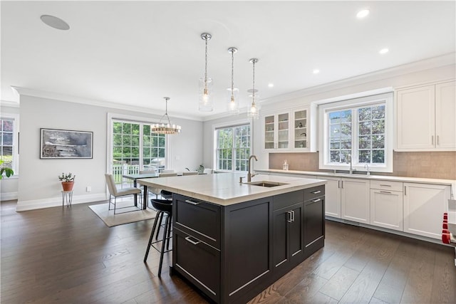 kitchen featuring white cabinets, dark hardwood / wood-style floors, pendant lighting, and a kitchen island with sink