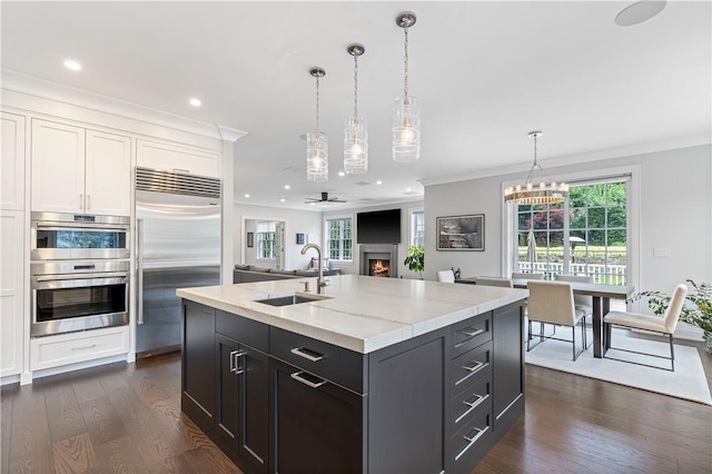 kitchen featuring stainless steel appliances, ceiling fan, a kitchen island with sink, sink, and dark hardwood / wood-style floors