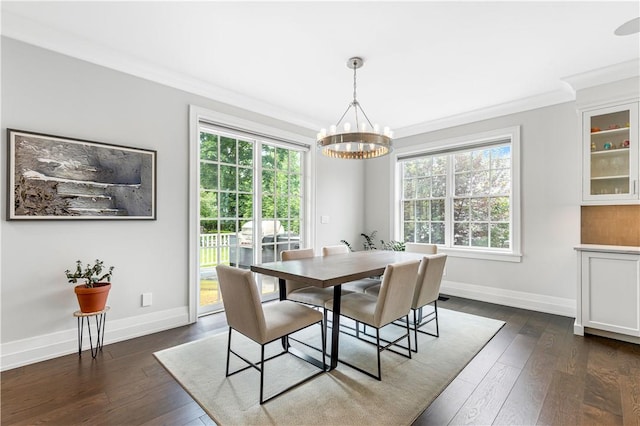 dining space with dark hardwood / wood-style floors, an inviting chandelier, plenty of natural light, and crown molding