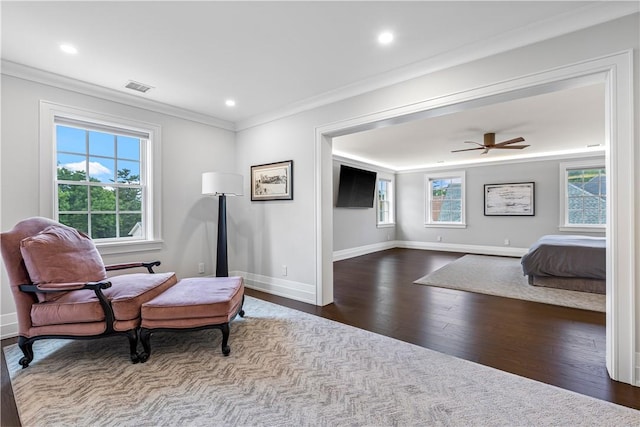 living area featuring ornamental molding, dark hardwood / wood-style floors, ceiling fan, and a healthy amount of sunlight