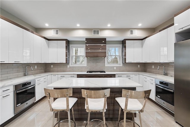 kitchen with a kitchen breakfast bar, light stone countertops, a kitchen island, and appliances with stainless steel finishes