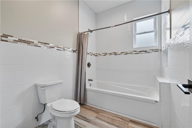 bathroom featuring shower / bath combination with curtain, toilet, and tile walls