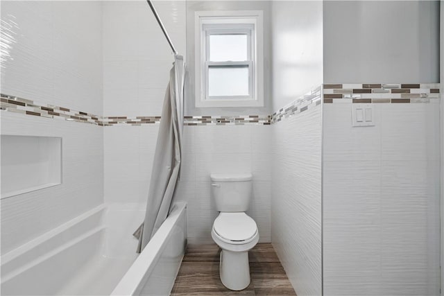 bathroom featuring hardwood / wood-style flooring, shower / bath combo, toilet, and tile walls