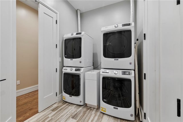 laundry room with stacked washer / drying machine and light hardwood / wood-style floors