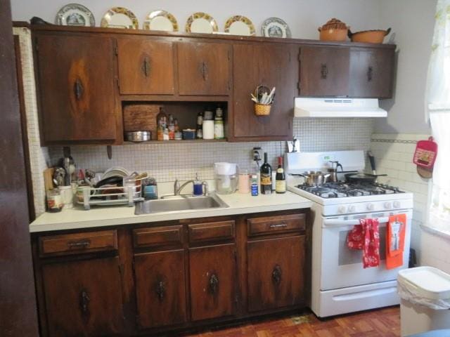 kitchen featuring backsplash, white gas stove, dark parquet flooring, and sink