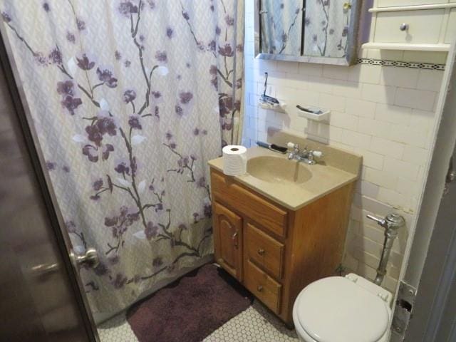 bathroom featuring vanity, backsplash, a shower with shower curtain, toilet, and tile walls