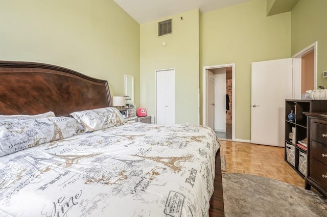 bedroom with a high ceiling, light parquet flooring, and a closet