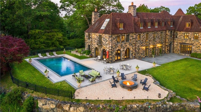 pool at dusk featuring a yard, a patio, and an outdoor fire pit