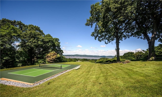 view of tennis court featuring a mountain view and a lawn