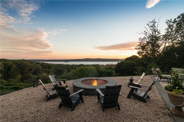 patio terrace at dusk featuring a fire pit and a water view