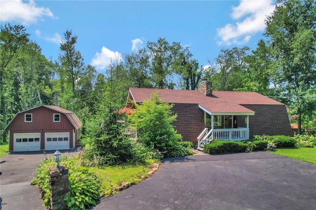 view of front of property featuring covered porch, a garage, and an outbuilding