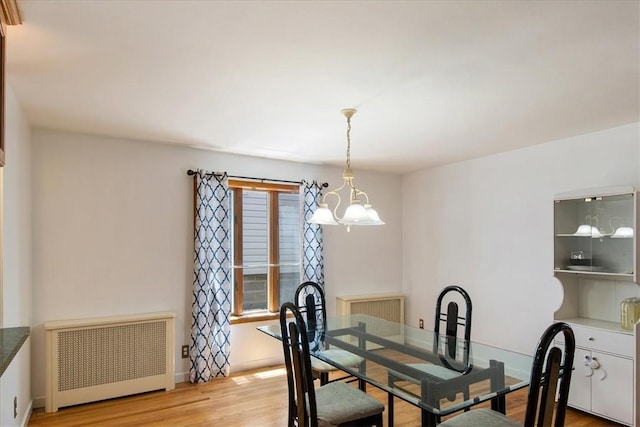 dining room with radiator, an inviting chandelier, and light wood-type flooring