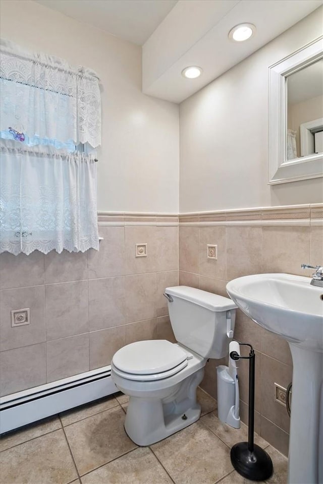 bathroom featuring tile patterned floors, toilet, tile walls, and a baseboard radiator