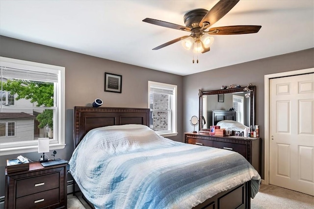 bedroom featuring multiple windows, ceiling fan, and light colored carpet