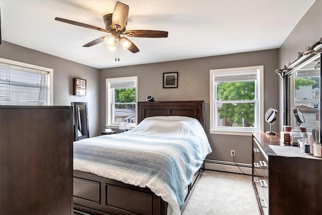 bedroom featuring multiple windows, ceiling fan, a baseboard radiator, and light carpet