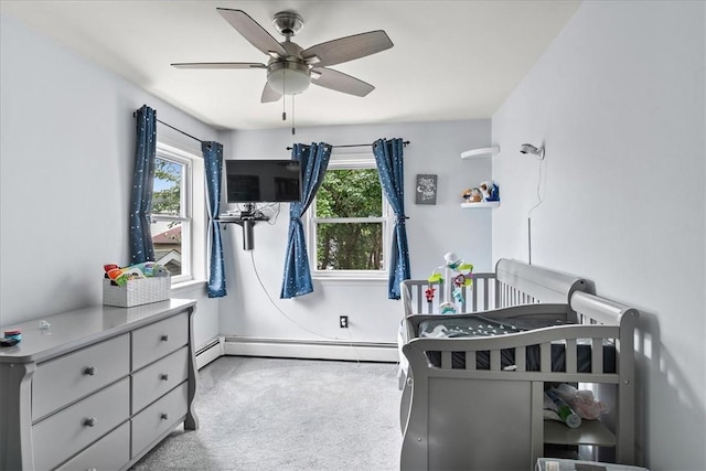 carpeted bedroom featuring multiple windows, ceiling fan, and a baseboard heating unit