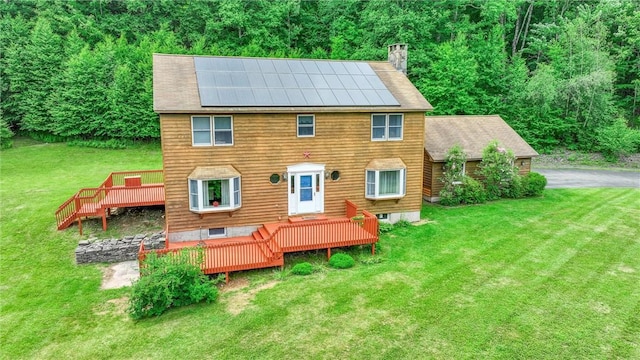 view of front of home featuring a wooden deck, a front lawn, and solar panels