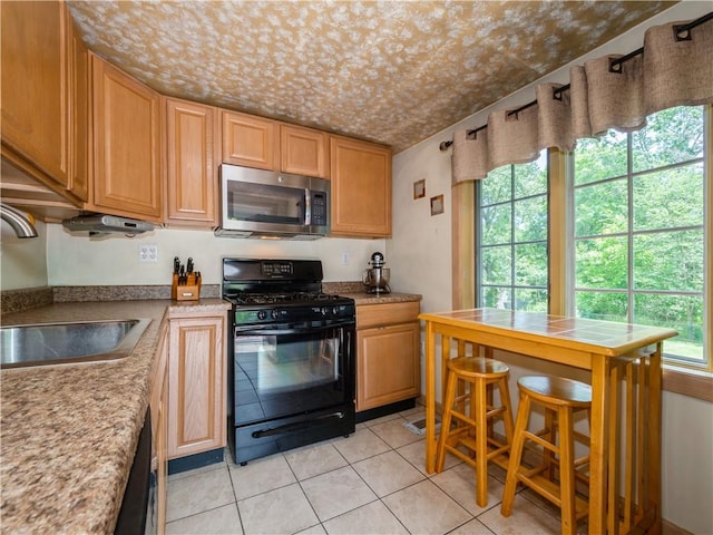 kitchen with light tile patterned floors, sink, and black appliances