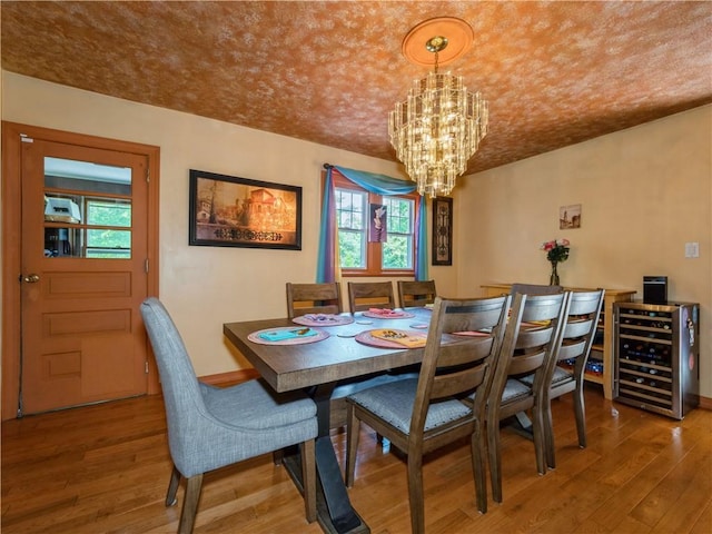 dining space with plenty of natural light, beverage cooler, hardwood / wood-style floors, and an inviting chandelier