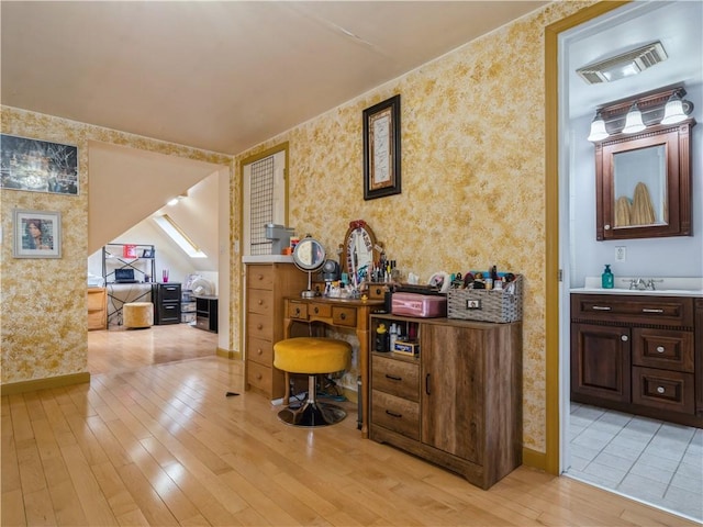 interior space with dark brown cabinets, light wood-type flooring, and sink