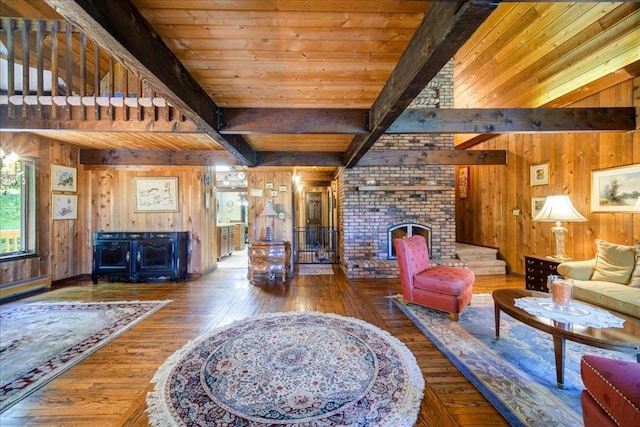 living room featuring beam ceiling, wood walls, a fireplace, and hardwood / wood-style flooring