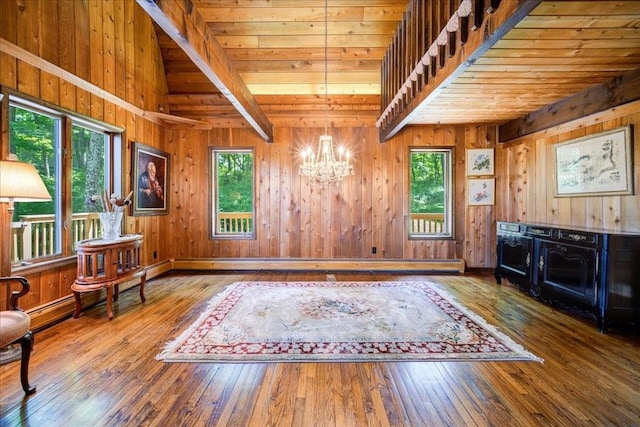 misc room featuring a chandelier, hardwood / wood-style floors, a healthy amount of sunlight, and wood walls