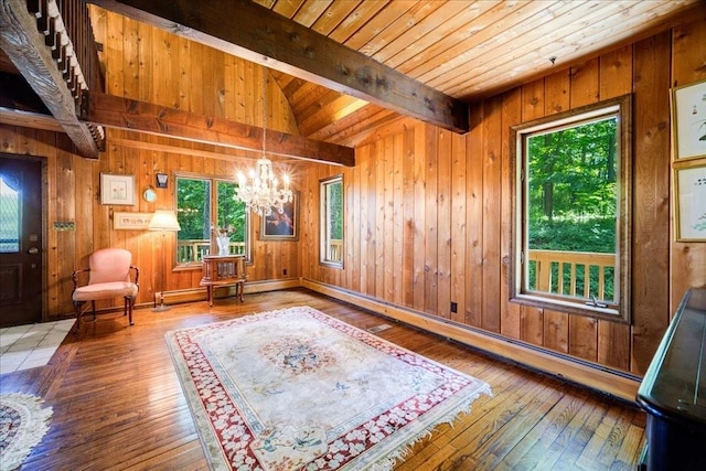 unfurnished room featuring lofted ceiling with beams, wood walls, and wood-type flooring