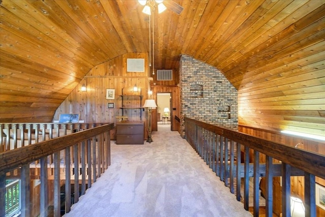 hallway featuring carpet flooring, lofted ceiling, wood ceiling, and wooden walls