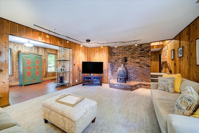 living room with wood walls, a wood stove, and track lighting