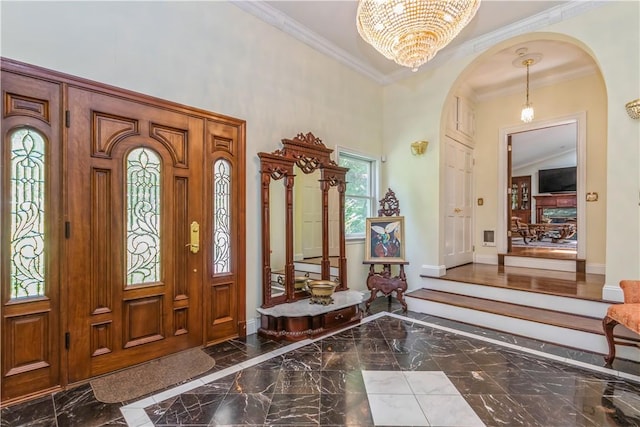 foyer featuring a chandelier, vaulted ceiling, and crown molding