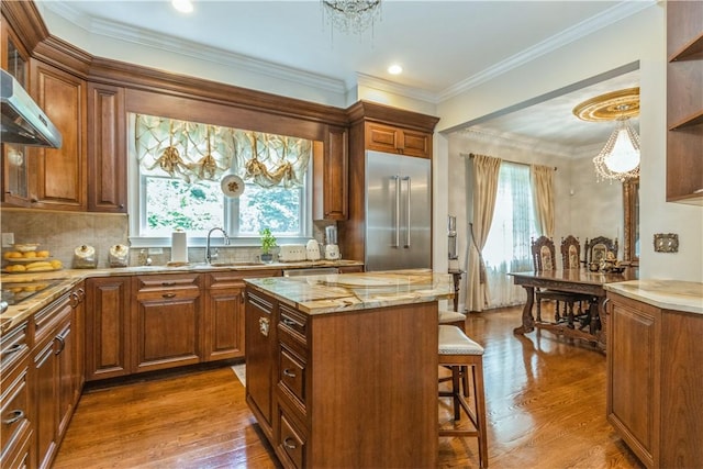 kitchen featuring built in fridge, a center island, a healthy amount of sunlight, and wood-type flooring