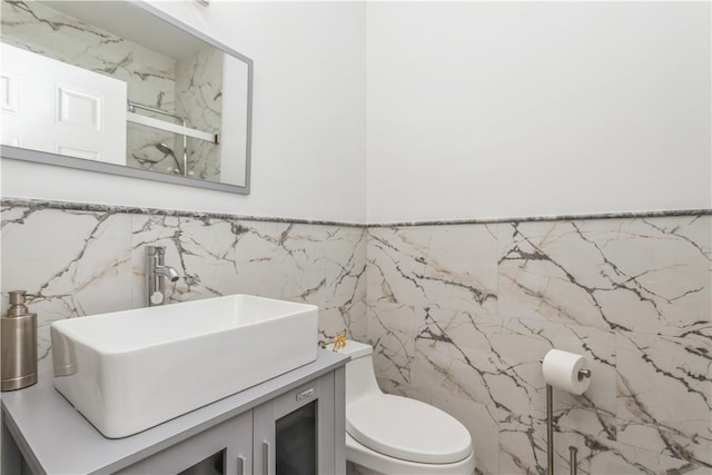 bathroom with vanity, toilet, and tile walls