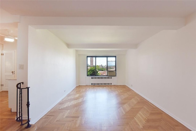 unfurnished room with light parquet flooring, radiator heating unit, and beamed ceiling