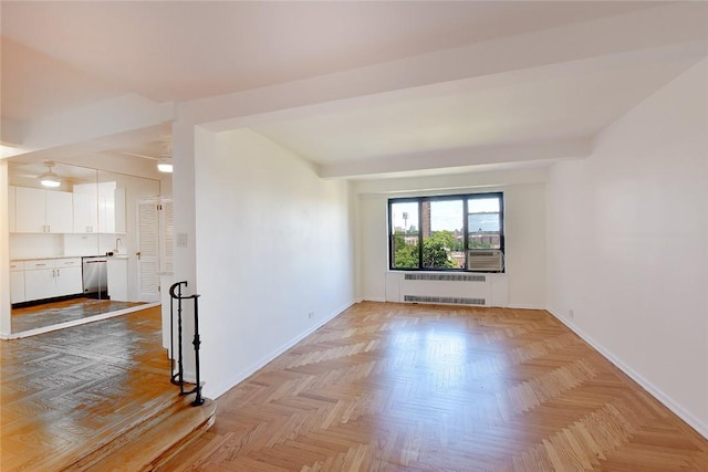 empty room featuring lofted ceiling, radiator, and light parquet flooring