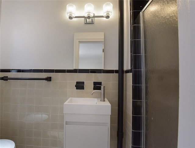 bathroom featuring a shower with door, vanity, and tile walls