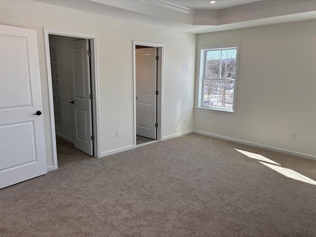 unfurnished bedroom featuring a raised ceiling and light carpet