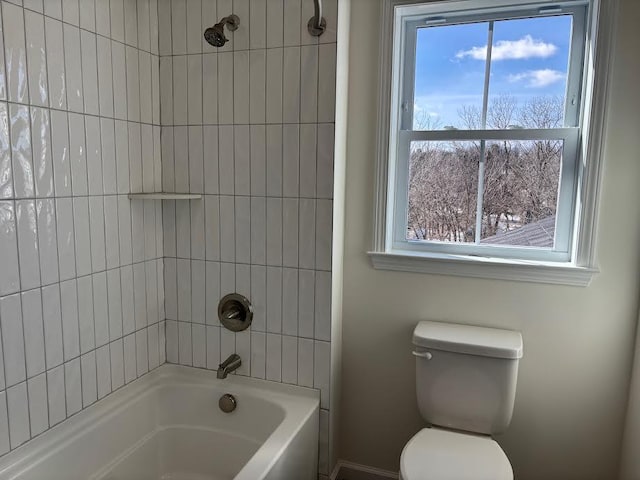 bathroom with toilet and tiled shower / bath