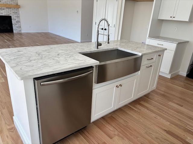 kitchen featuring sink, a center island with sink, white cabinetry, and dishwasher