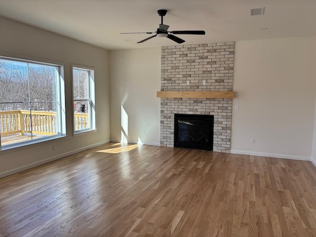 unfurnished living room with hardwood / wood-style flooring, a brick fireplace, and ceiling fan