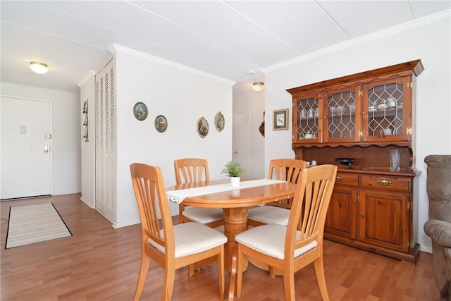 dining space with light hardwood / wood-style flooring and ornamental molding