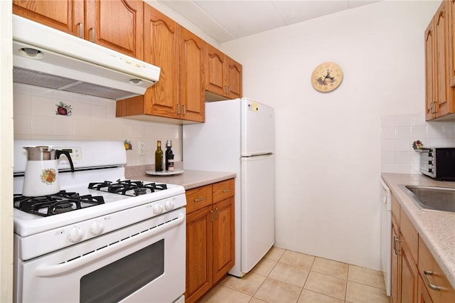 kitchen featuring light tile patterned flooring, white appliances, sink, and tasteful backsplash