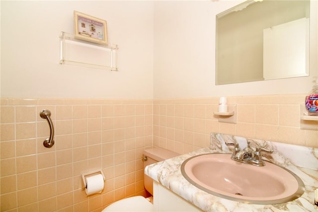 bathroom with vanity, toilet, and tile walls