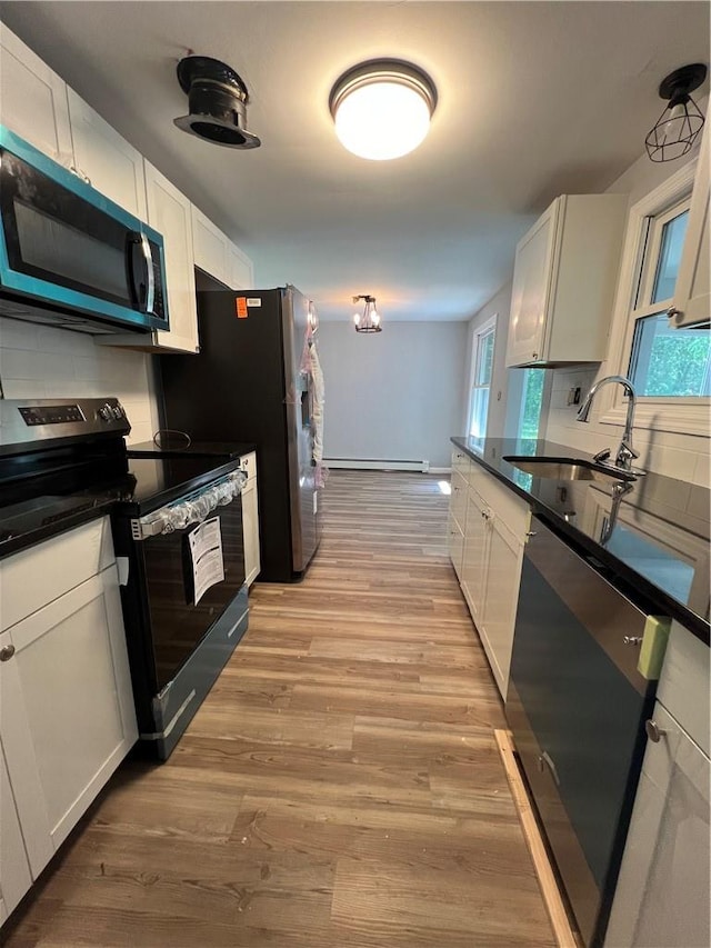 kitchen featuring white cabinetry, sink, light hardwood / wood-style floors, decorative backsplash, and appliances with stainless steel finishes