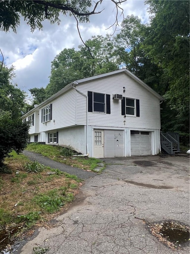 view of front facade featuring a garage and a wall unit AC