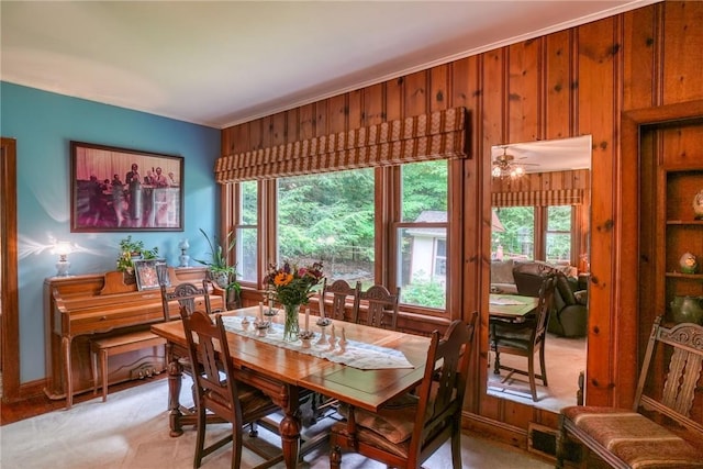 dining room featuring ceiling fan and wooden walls