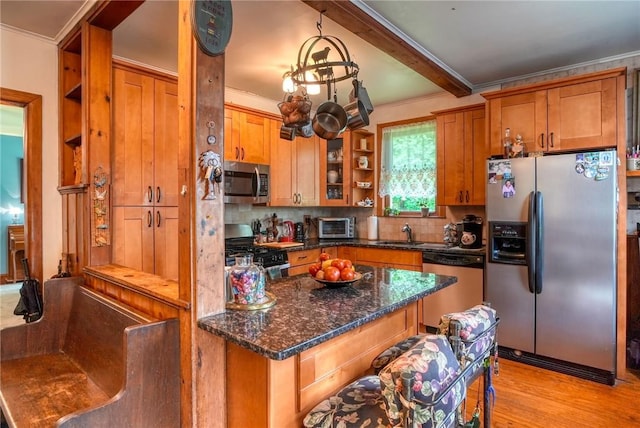 kitchen featuring sink, stainless steel appliances, dark stone counters, light hardwood / wood-style floors, and decorative backsplash