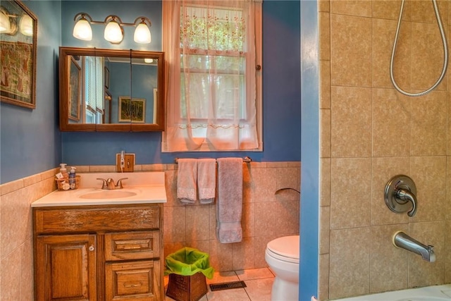 bathroom with tile patterned flooring, vanity, toilet, and tile walls